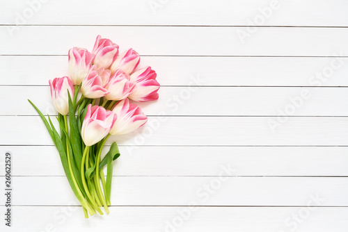 Bouquet of pink tulips on white wooden background. Top view, copy space. Greeting card.