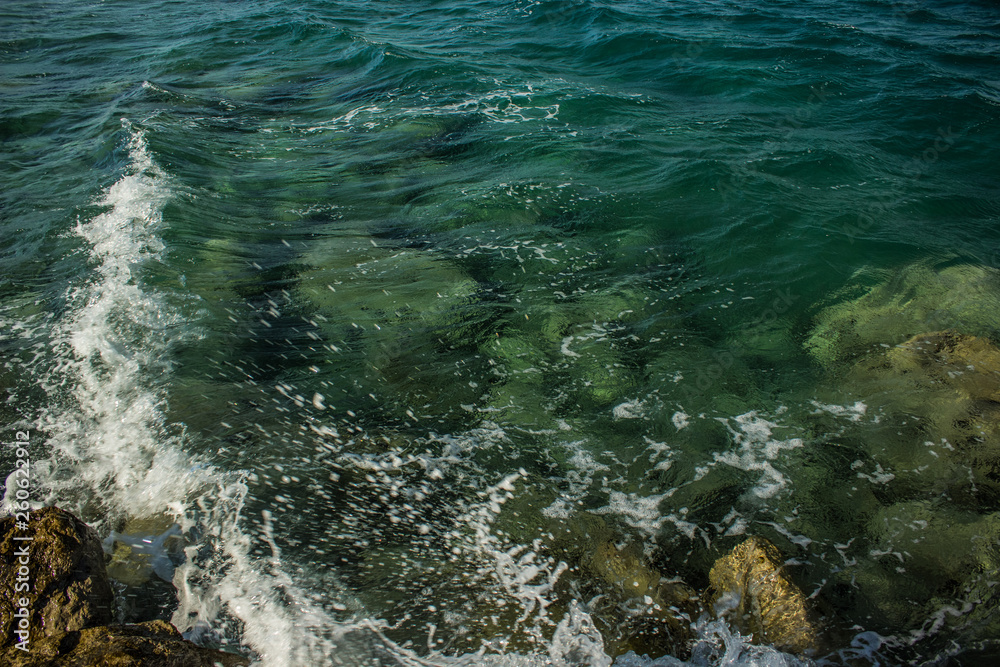 waterfront transparent green water surface natural background local scenic landscape from above with waves breaking on stone