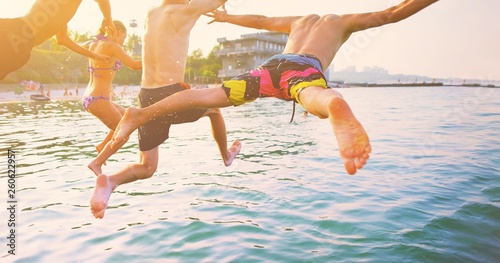 Group of happy crazy people having fun jumping in the sea water from boat. Friends jump in mid air on sunny day summer pool party at diving holiday. Travel vacation, friendship, youth holiday concept.