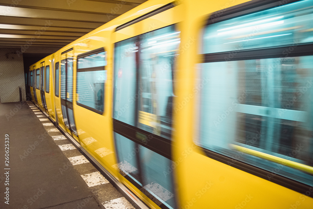 Fototapeta premium Yellow blurred subway train in Berlin. Public U-bahn transport in underground station interior