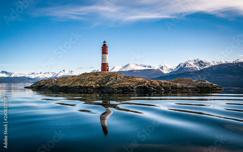 The lighthouse at world's end. Island with lighthouse on a peaceful lake, snowy mountains landscape on a perfect weather day. photo