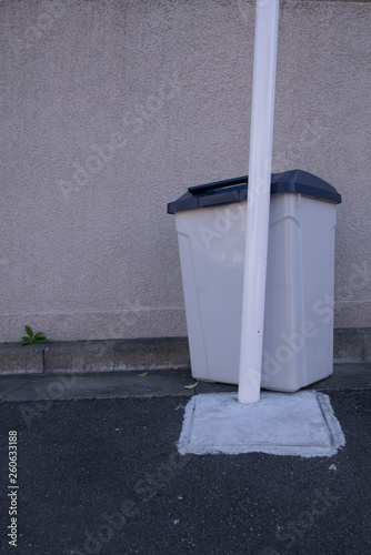 A trash box behind a street sign pole