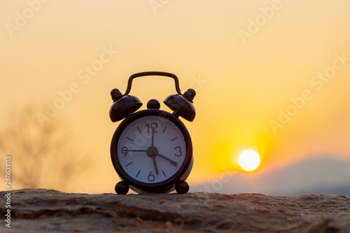 Clock on the stone at sunset nature background. vintage style