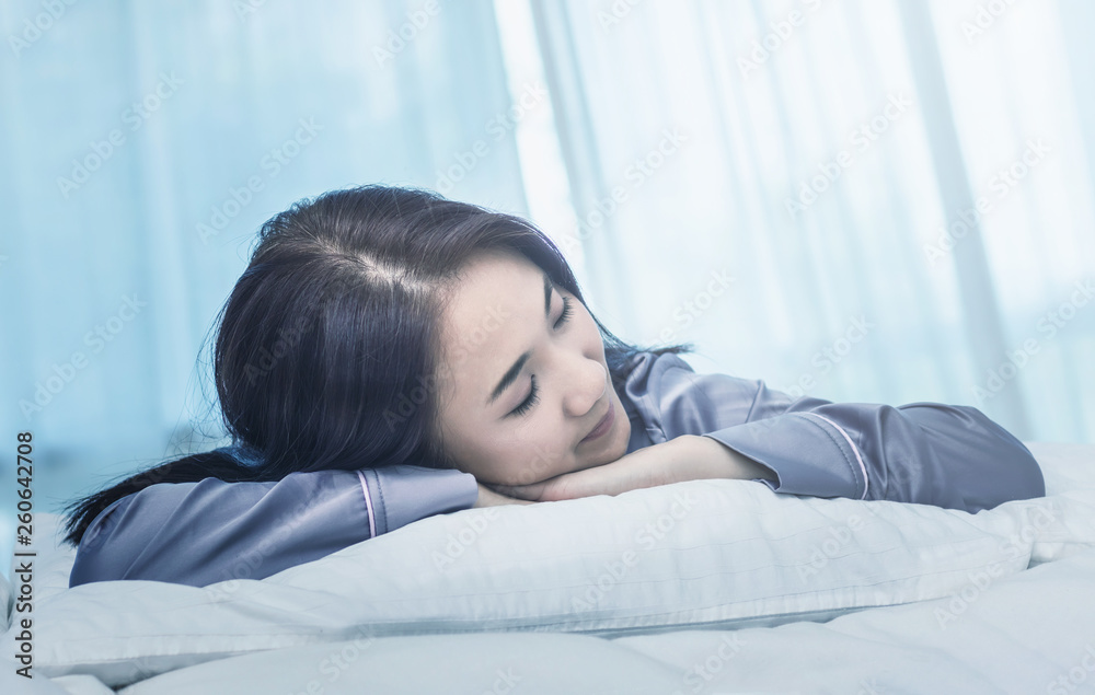 Asian woman sleep on white pillow on bed in bedroom in holiday.happy relax time.color tone Asian woman sleep on white pillow on bed in bedroom in holiday.happy relax time.color tone