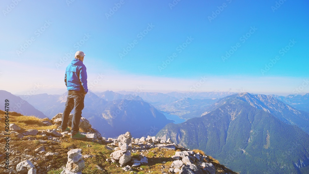 Traveler man relaxing standing and enjoying serene view mountains and lake landscape. Travel Lifestyle hiking concept spring autumn vacations outdoor. Austria Alps Dachstein Krippenstein five fingers