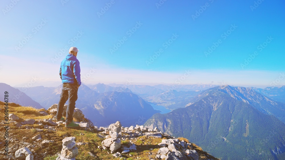 Fototapeta premium Traveler man relaxing standing and enjoying serene view mountains and lake landscape. Travel Lifestyle hiking concept spring autumn vacations outdoor. Austria Alps Dachstein Krippenstein five fingers