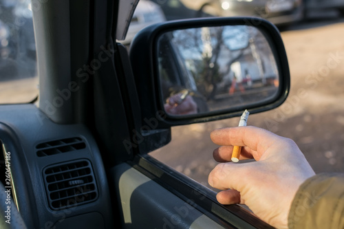 close-up, smoking cigarette in the hand of a man, the driver, in the car, which is in the Parking lot © Евгений Медведев