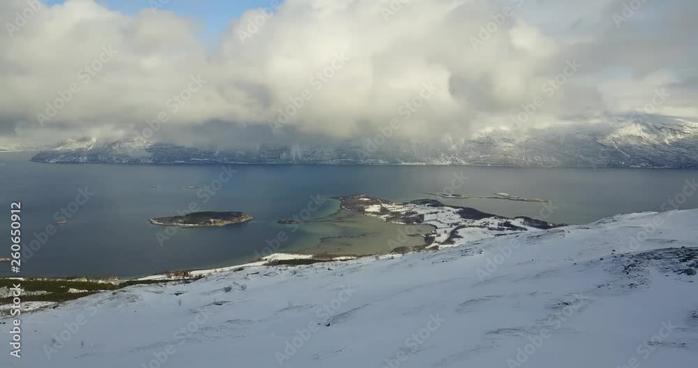 rotating  drone shot over the top of snow rock mountain.low angle clouds scattered all over the place.the sun trying to shine as much as possible.beautiful winter destination norway.shot in 4K 24fps