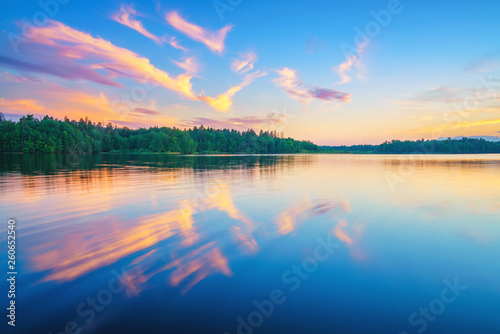 Beautiful landscape with colorful sunset over forest lake