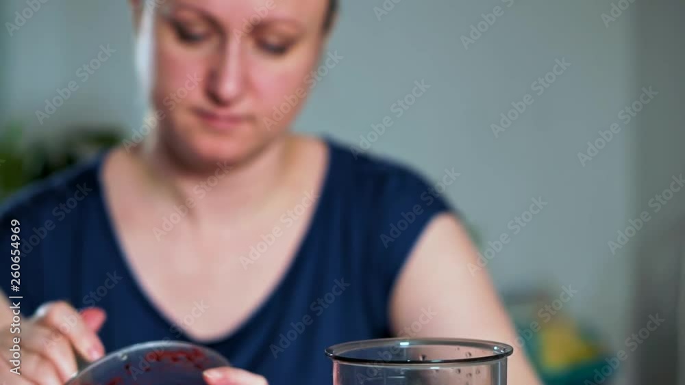 The concept of healthy eating. Close-up of a woman puts a spoon of fruit and berry puree in a blender. She makes herself a delicious and healthy smoothie The concept of healthy eating. Close-up of a woman puts a spoon of fruit and berry puree in a blender. She makes herself a delicious and healthy smoothie