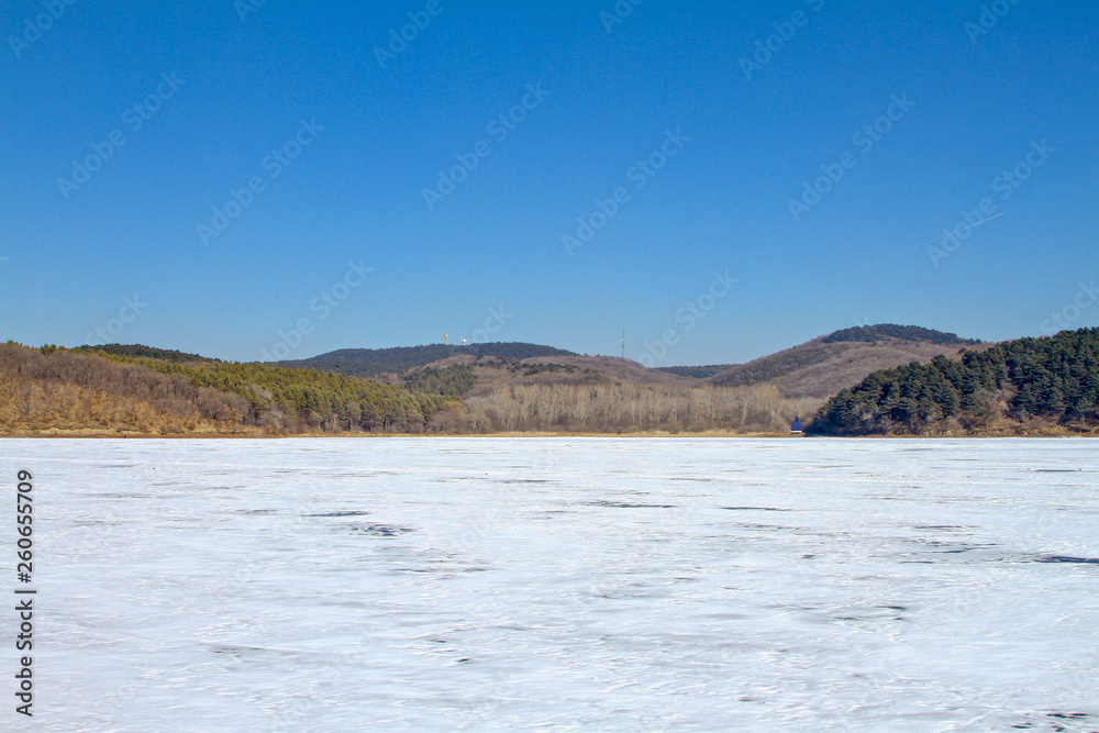 Landscape of frozen lake covered by snow in winter