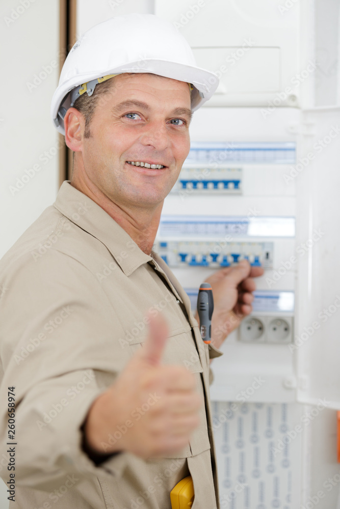 portrait of electrician standing next to fuseboard portrait of electrician standing next to fuseboard