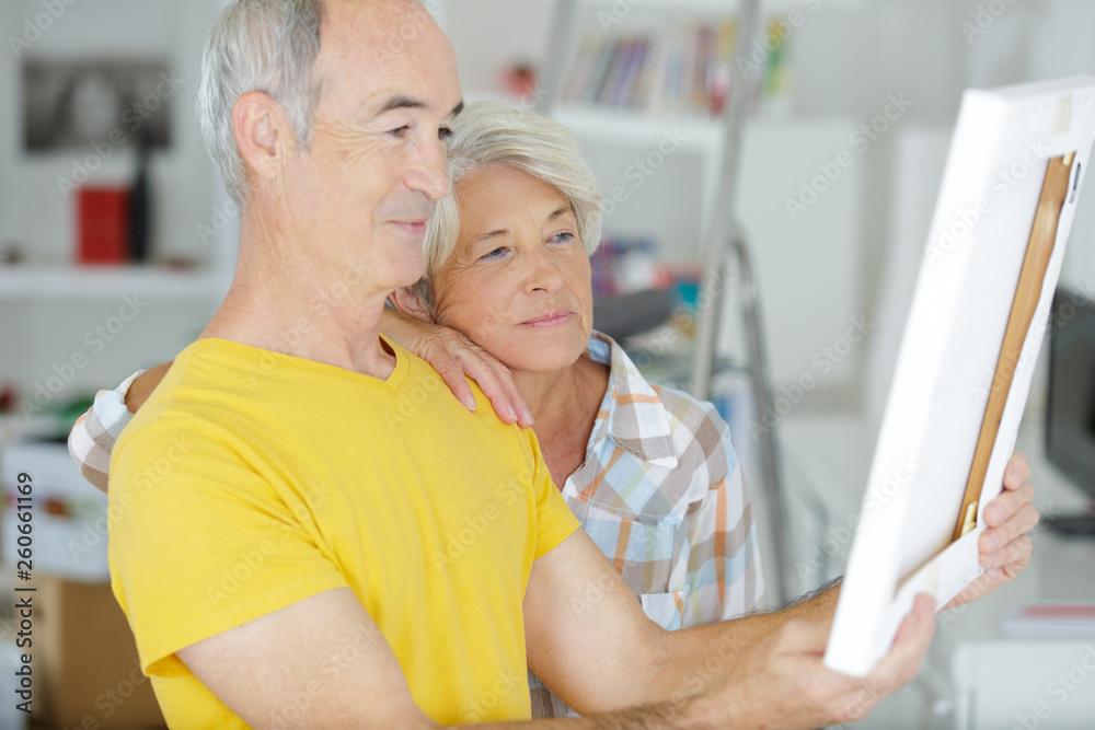 senior couple looking at photograph in frame together senior couple looking at photograph in frame together