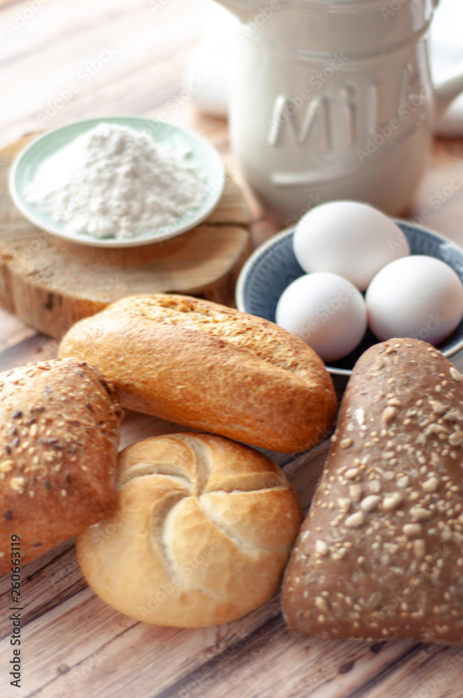 Various baked breads and rolls on wooden table