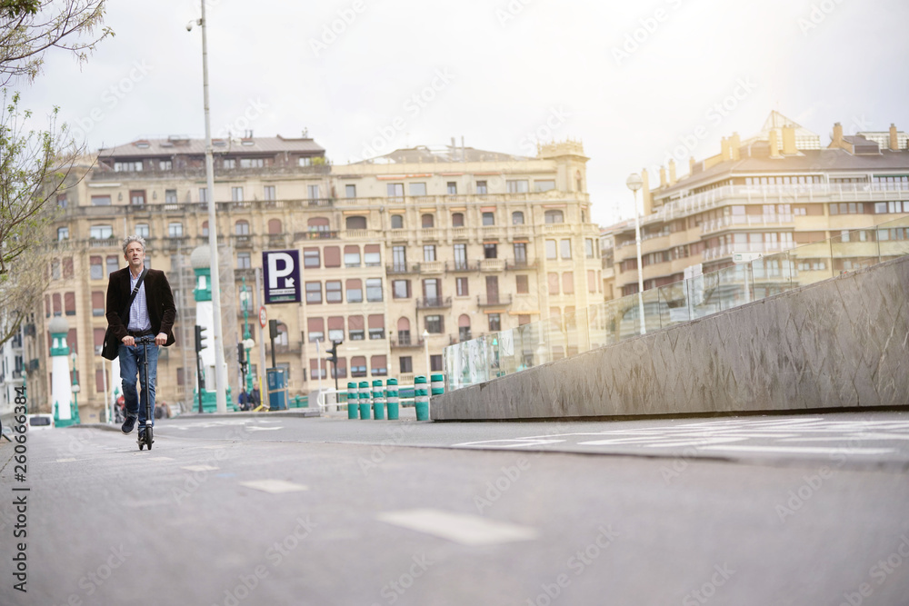 Businessman on daily commute riding micro scooter