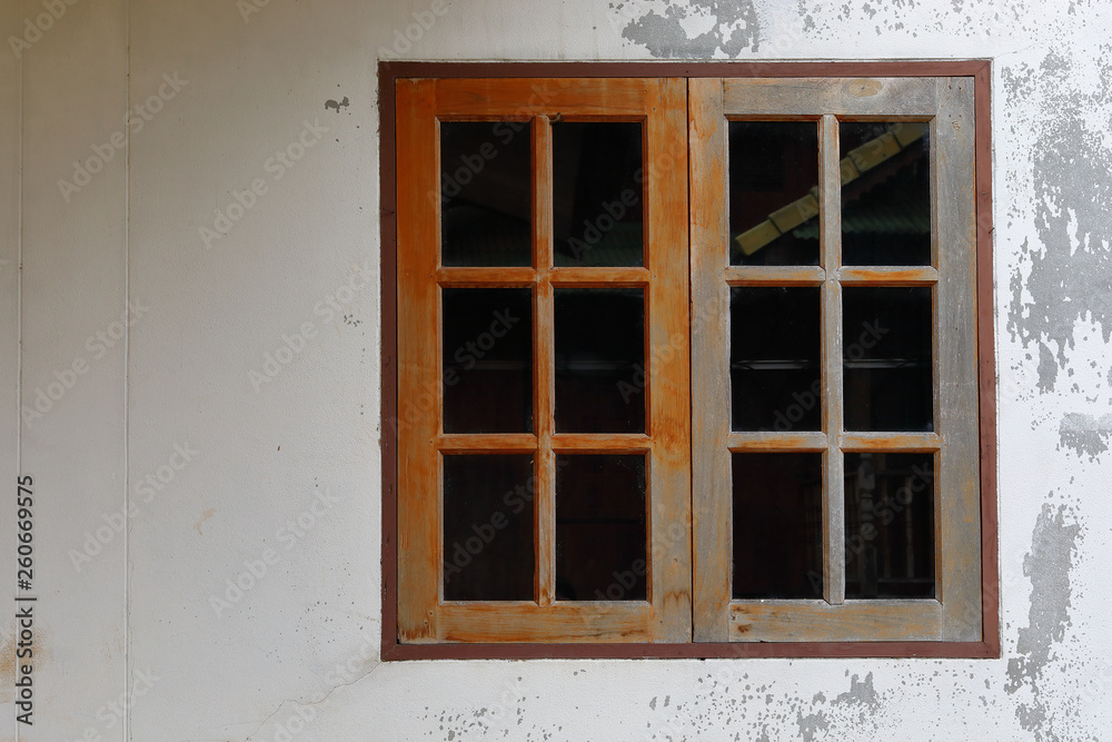 old glass window with wooden frame on weathered wall