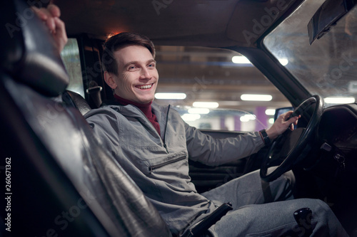 Image from side of happy man looking at camera sitting in car. © Sergey