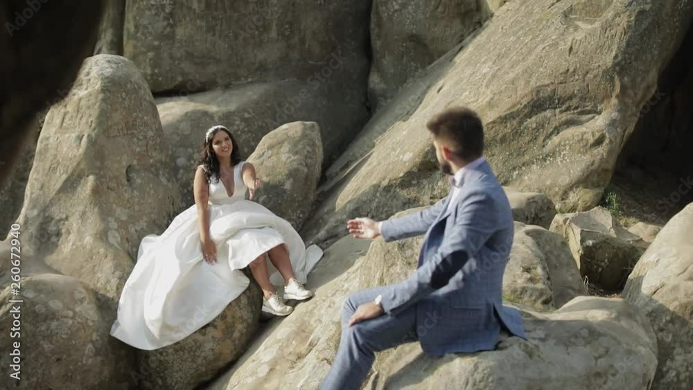 Groom with bride sit on a slope of the mountain. Wedding couple. Happy Groom with bride sit on a slope of the mountain. Wedding couple. Happy