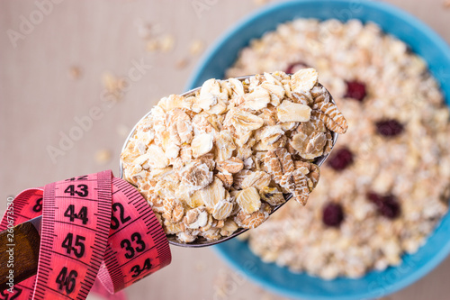 Oatmeal in bowl and measuring tape around spoon