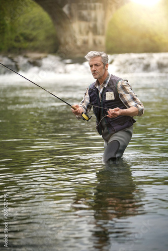 Mature man fly fishing in beautiful river