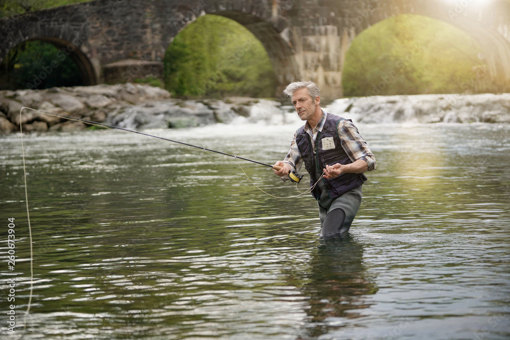 Mature man fly fishing in beautiful river Mature man fly fishing in beautiful river