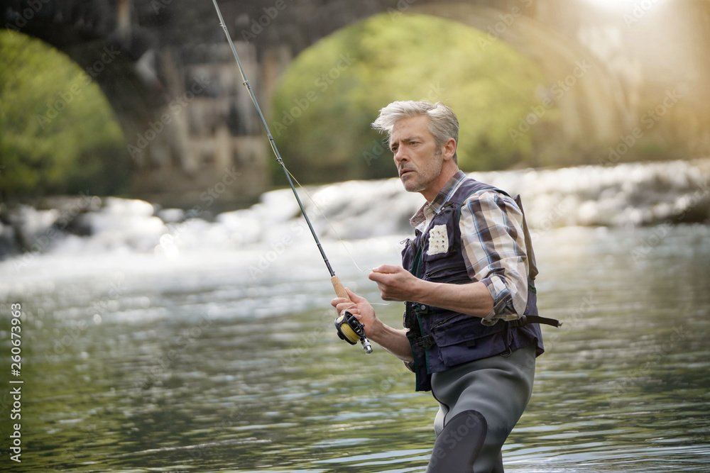Mature man fly fishing in beautiful river Mature man fly fishing in beautiful river