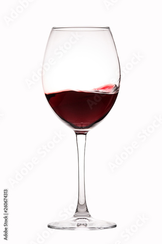 Red wine splashes in a glass on white background