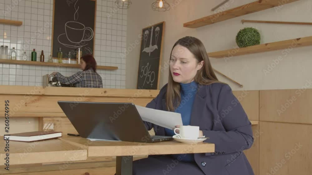 Professional real estate agent networking online at cafe table with cup of coffee, typing on laptop, talking on cellphone with customer. Independent businesswoman working in cafe during coffee break. Professional real estate agent networking online at cafe table with cup of coffee, typing on laptop, talking on cellphone with customer. Independent businesswoman working in cafe during coffee break.