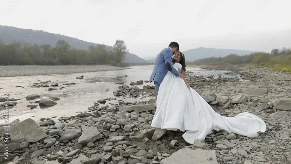 Wedding couple standing near mountain river. Groom and bride in love Wedding couple standing near mountain river. Groom and bride in love