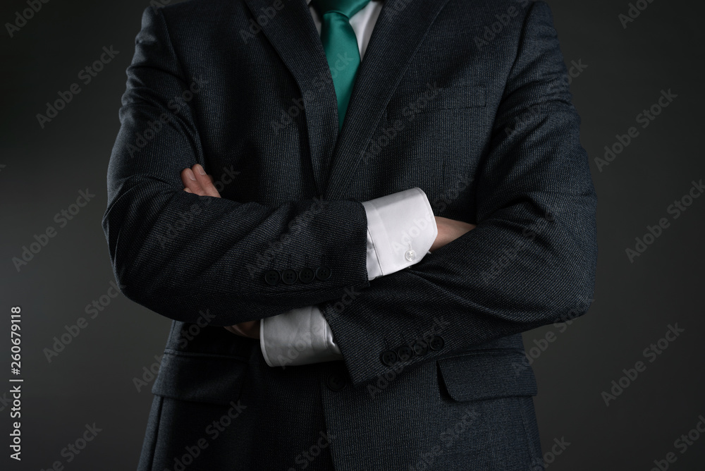 Businessman with a crossed hands on a gray background. Business acumen. Strict boss.