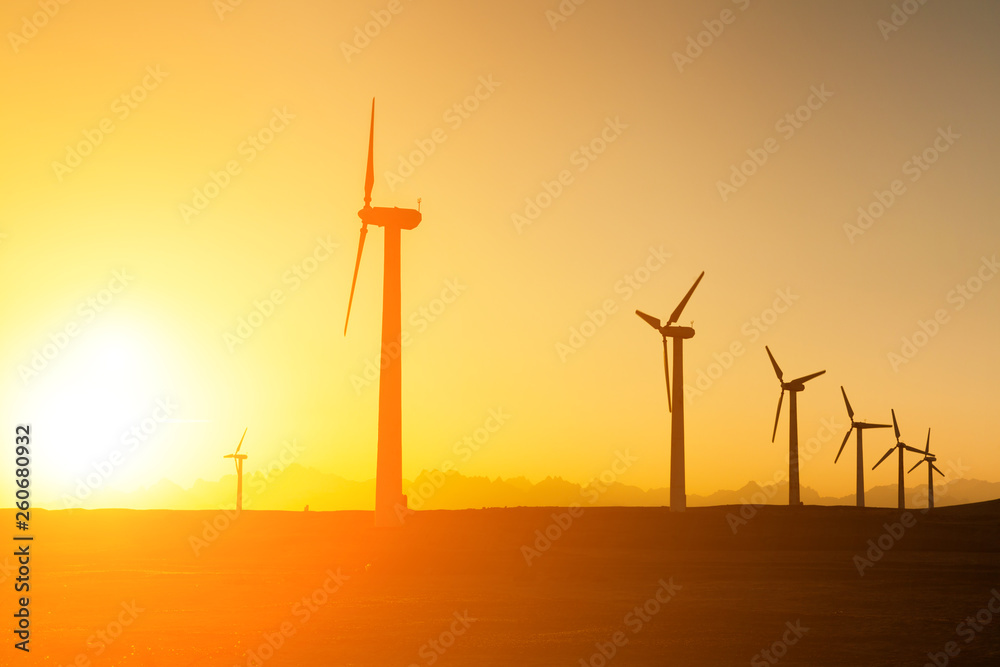 Obraz premium Big wind turbines in the desert at sunset background