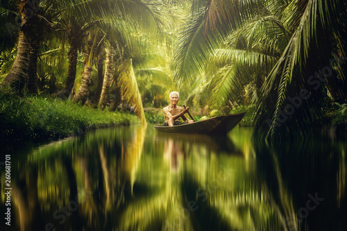 Old man collecting coconut by using boat in cococut farm photo