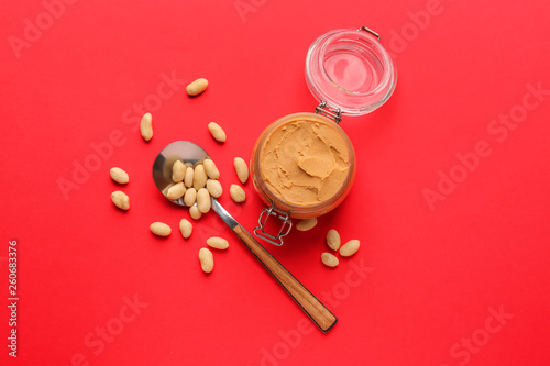 Jar with peanut butter on color background