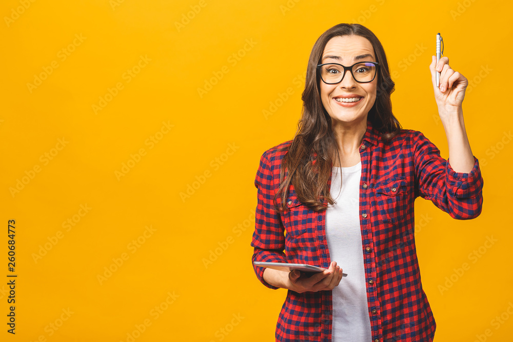 Having idea! Portrait with copy space empty place of pretty charming confident happy woman in casual having tablet and pen in hands isolated against yellow background. Having idea! Portrait with copy space empty place of pretty charming confident happy woman in casual having tablet and pen in hands isolated against yellow background.