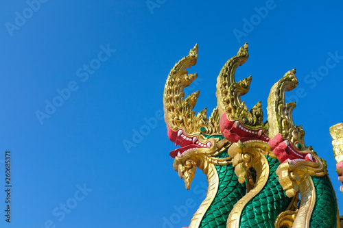 Thai Naka  big snake  serpent statue on clear bright blue sky. Mythical creature in Buddhism belief. Traditional Thai style architecture
