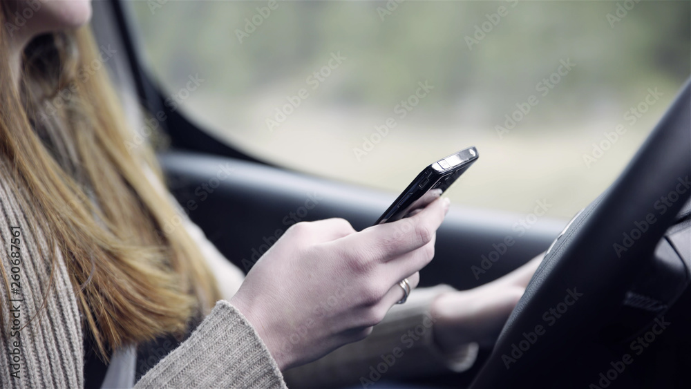 Person writing on smartphone while driving car