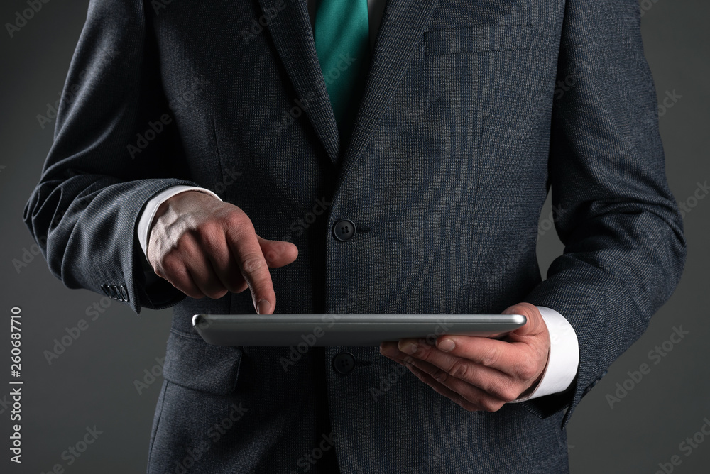 Digital tablet computer in a business man hands on gray background. Buy or sale online. Internet work.
