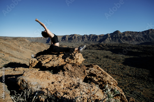 The girl practices yoga in the mountains. Volcano Teide on the background.