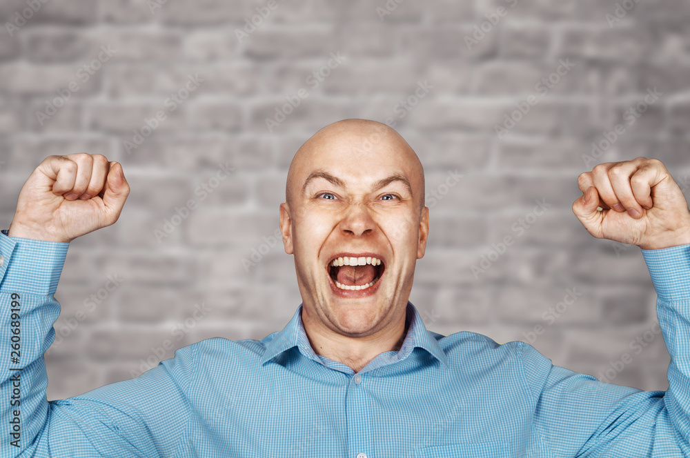 Naklejka premium Portrait White bald guy in blue shirt on white Brick wall background showing thumbs up and smiling