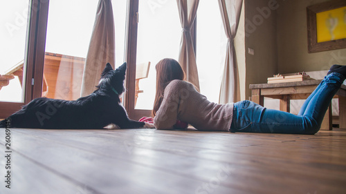 Woman and dog on home floor looking through window