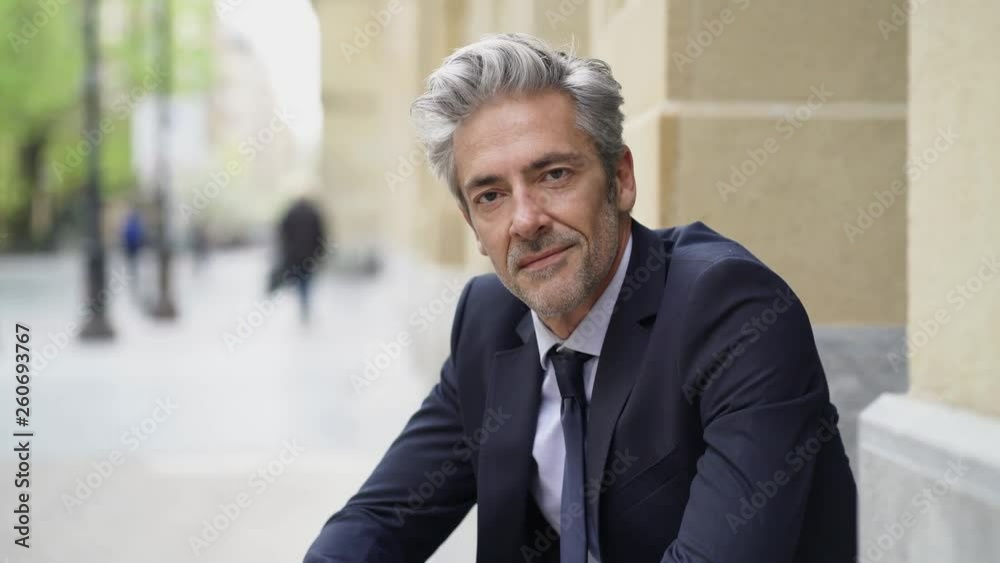 Businessman sitting outdoors looking at camera 