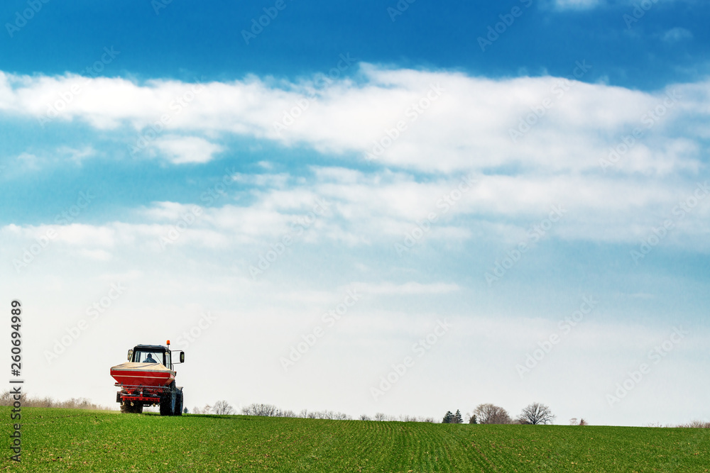 Agricultural tractor fertilizing wheat crop field with NPK Agricultural tractor fertilizing wheat crop field with NPK