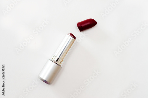 open case with broken Burgundy lipstick on white background