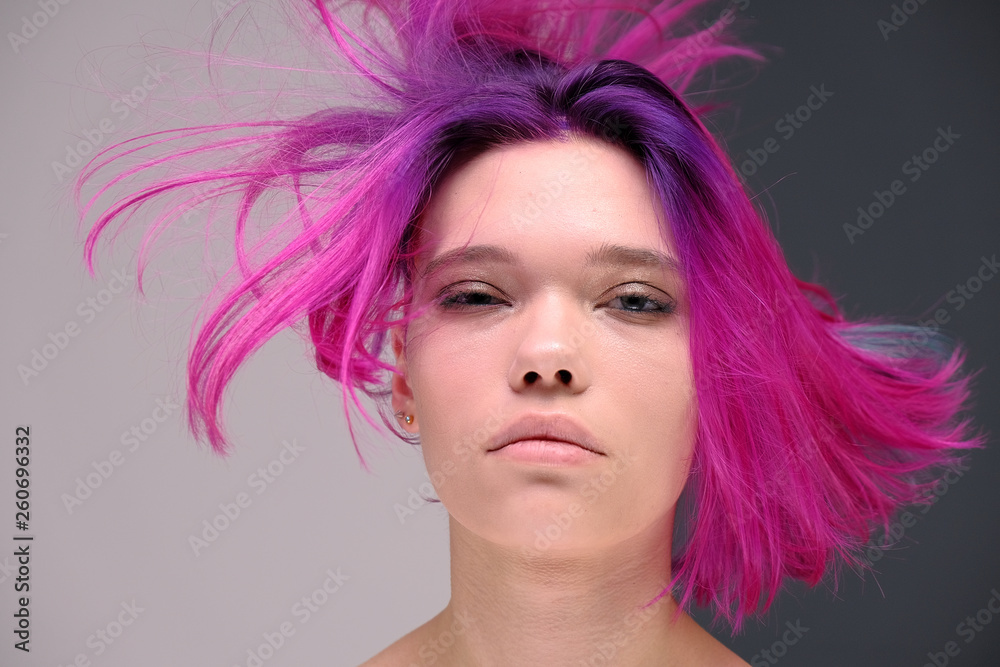 Concept Portrait of a punk girl, young woman with chic purple hair color in studio close up on a colorful background with fluttering hair. Concept Portrait of a punk girl, young woman with chic purple hair color in studio close up on a colorful background with fluttering hair.