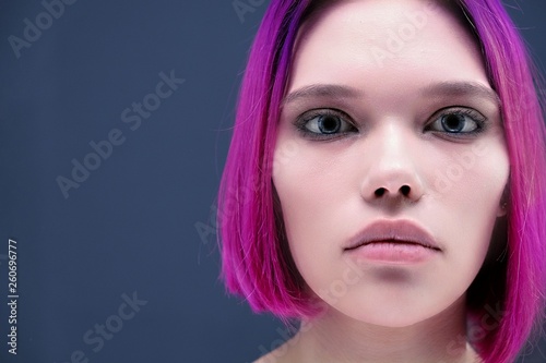 Concept Portrait of a punk girl  young woman with chic purple hair color in studio close up on a colorful background with fluttering hair.