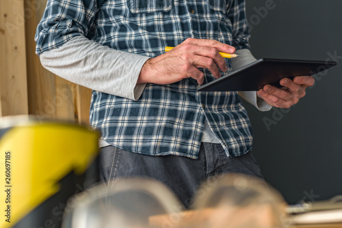 Fotografie Solopreneur carpenter using digital tablet in small business woodwork workshop