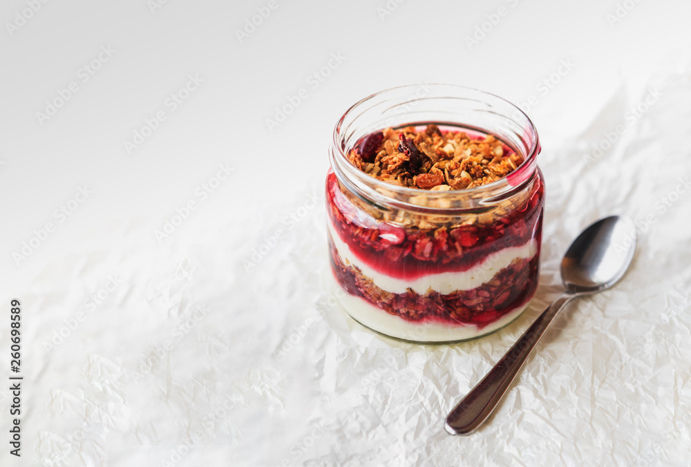 Fototapeta premium Summer fruit red berry breakfast. Healthy cherry split breakfast with cream cheese, granola, nuts and dried fruits white chocolate. In mason jar, on table. Copy space