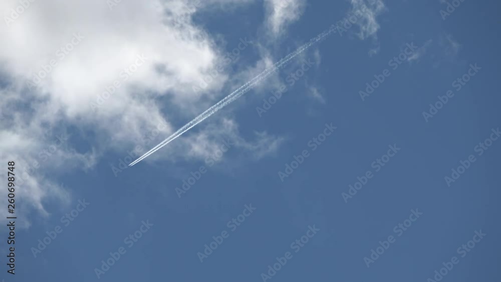 Jet trails across a cloudy blue sky closer prop plane flies in front Jet trails across a cloudy blue sky closer prop plane flies in front