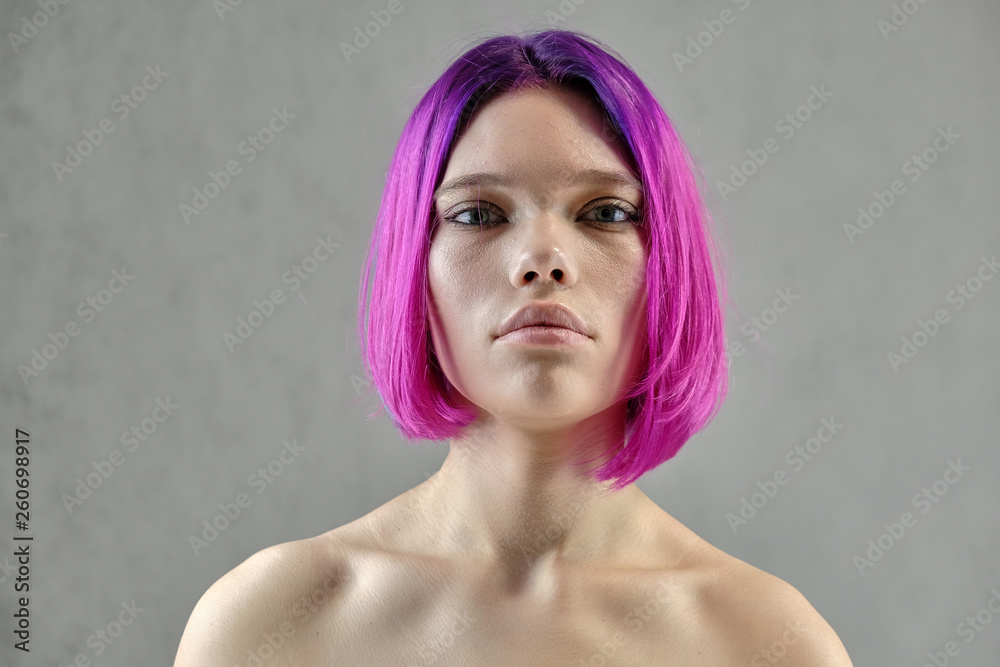 Naklejka premium Concept Portrait of a punk girl, young woman with chic purple hair color in studio close up on a colorful background with fluttering hair.