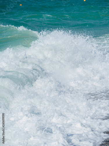 Splashes of water and foam against the sea on a sunny summer day